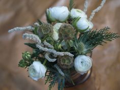 a vase filled with white flowers and greenery