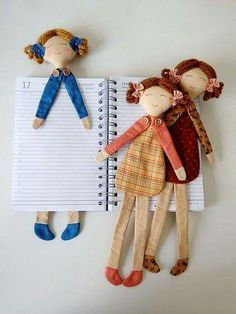 two dolls are hanging on the wall next to a notepad