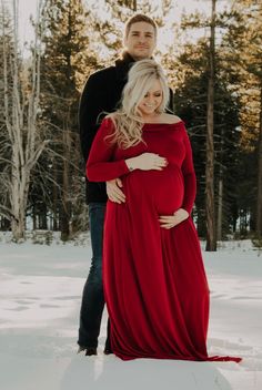 a pregnant couple standing in the snow