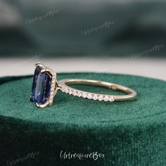 an engagement ring with a blue sapphire and diamonds on top of a green velvet box