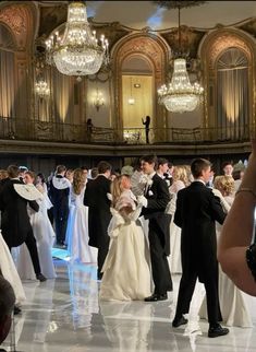 a group of people standing around each other in front of a chandelier filled with lights