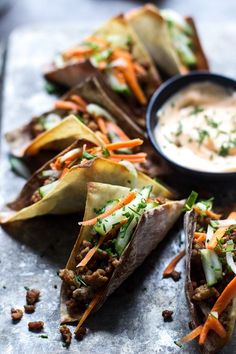 some tacos with carrots, celery and other toppings next to a bowl of ranch dressing