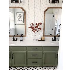 a bathroom with green cabinets and black and white floor tiles on the walls, along with a vase filled with flowers