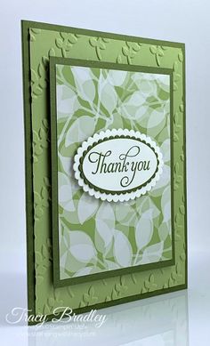 a thank you card with green leaves on the front and white lettering that reads, thank you