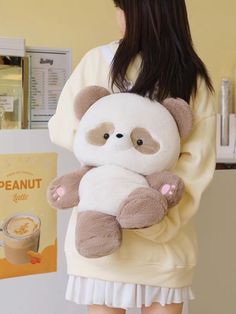 a woman holding a stuffed panda bear in her arms while standing next to a coffee machine