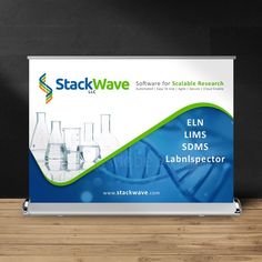 a roll up banner stands on a wooden table next to a blackboard with an image of laboratory equipment in it