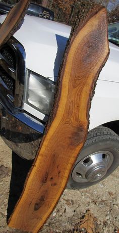 a white truck parked next to a tree with a large piece of wood sticking out of it's trunk