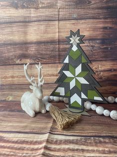 a small christmas tree sitting on top of a wooden table next to a white deer