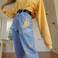 a woman in yellow shirt and blue jeans with moon and stars on her back legs