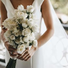 a woman holding a bouquet of white flowers