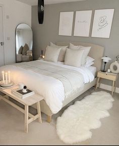 a white bed sitting in a bedroom next to a mirror