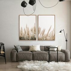 two paintings hanging on the wall above a couch in a living room with white fur rugs