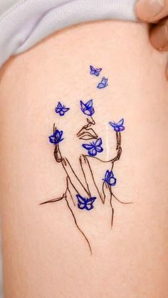 a woman's thigh with blue flowers and butterflies drawn on it, in the shape of a tattoo