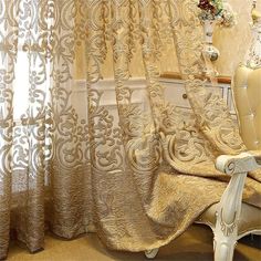 the curtains in this room are gold and there is a white chair next to it