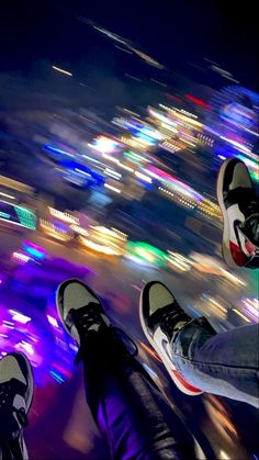 two people standing on top of a building with their feet in the air at night