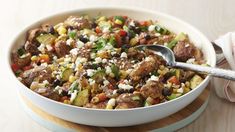 a white bowl filled with meat, vegetables and feta cheese