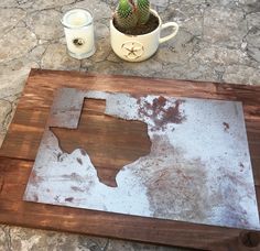 a wooden table topped with a potted cactus next to a white mug