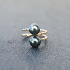 Two beautiful Tahitian pearls are set on a double bypass band. Wire is gold filled and will NOT tarnish! (Sterling silver also available) Tahitian pearls are approximately 9mm in size, and near round in shape. Quality is A/AB. Hues may vary one from another for each ring. This ring is made to order according to your selected ring size, please be sure of your size before ordering. Resizing is subjected to fees. Yellow Gold Tahitian Pearl Ring Gift, Elegant Yellow Gold Tahitian Pearl Rings, Black Tahitian Pearl Ring, Luxury Tahitian Pearl Ring, Luxury Tahitian Pearl Ring, Round Shape, Tahitian Pearl Ring, Hawaiian Jewelry, Tahitian Pearls, Black Pearl