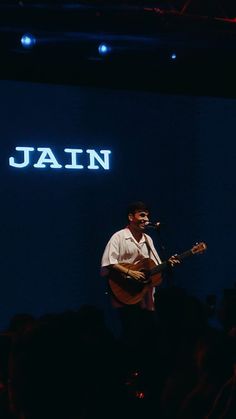 a man standing on top of a stage holding a guitar