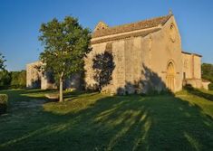 an old stone building with trees in the foreground