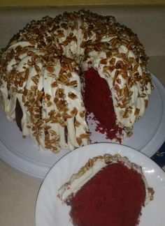 a red velvet cake with white frosting and pecans on the top is cut in half