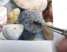 a person is painting rocks with watercolors on paper