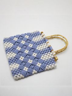 a crocheted blue and white purse with gold handles on a white surface,