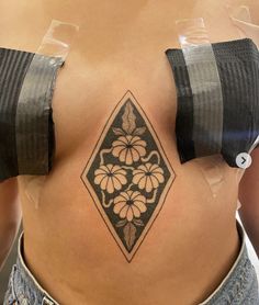 a woman's stomach with a tattoo on her side and flowers in the center