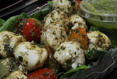 a tray filled with different types of food next to a bowl of pesto sauce