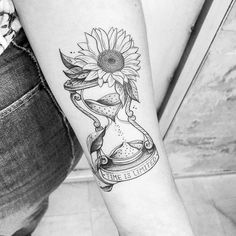 a woman's arm with a sunflower and an hourglass tattoo on it