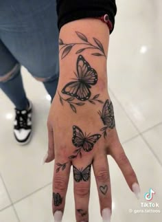 a woman's hand with tattoos on it and two butterflies flying around the wrist