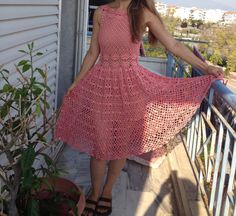 a woman in a pink dress standing on a porch