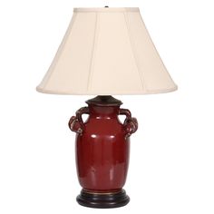 a red vase lamp with a white shade on the top and bottom, sitting in front of a white background