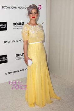 a woman in a yellow dress posing for a photo on the red carpet at an event