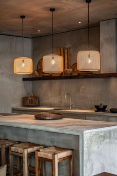 a kitchen counter with stools and lights above it in an industrial style home setting