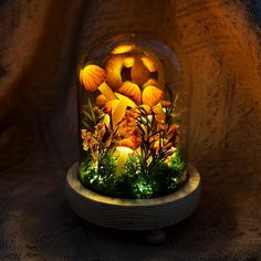 a glass dome with mushrooms and plants inside on a wooden stand in front of a dark background