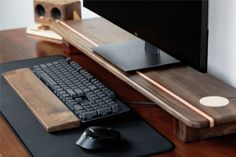 a computer desk with a keyboard, mouse pad and wooden monitor stand on top of it