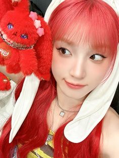 a girl with long red hair holding a stuffed animal