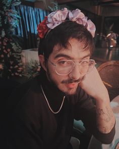 a man sitting at a table with a flower in his hair and glasses on top of his head