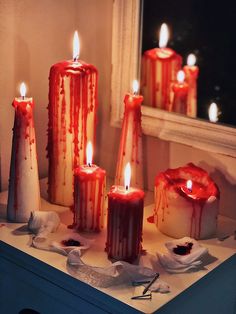 five candles with blood running down them on a table next to a window sill