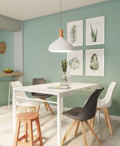 a dining room table with four chairs and pictures on the wall above it, along with two stools