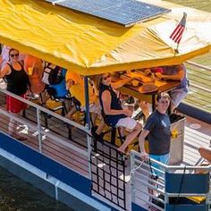 a group of people riding on the back of a boat with solar panels over it