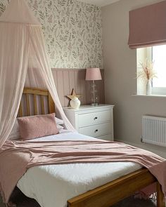 a bed with a pink canopy over it in a bedroom next to a dresser and window