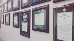 a wall full of framed pictures and plaques on it's side, along with an award plaque