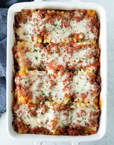 lasagna casserole with meat and cheese in a white dish on a blue towel