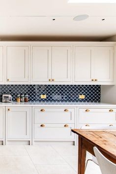 a kitchen with white cabinets and blue backsplash tiles on the countertops, along with a wooden dining table