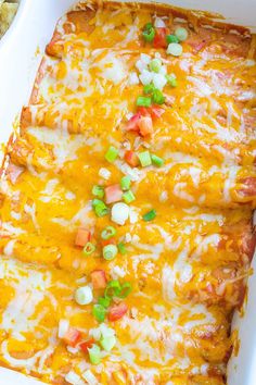 an enchilada casserole in a white dish with green onions and carrots