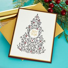 a card with a christmas tree on it and some red berries in front of it