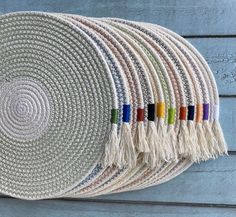 a wall hanging made out of woven material with colorful tassels on the ends