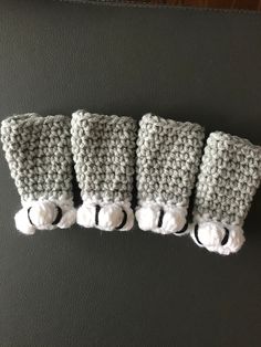 four crocheted hand warmers hanging on the wall